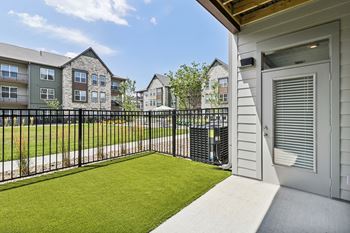 The yard of a condo with a green lawn and a fence
